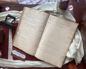 artifacts on display: cast iron iron, ledger book with transaction details